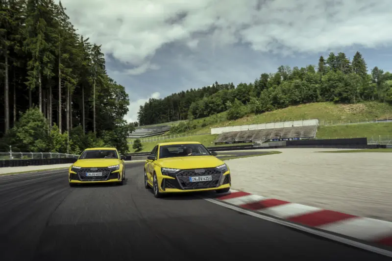 Két Audi RS 3 Sportback sárga színben dinamikus versenypályás fotón.